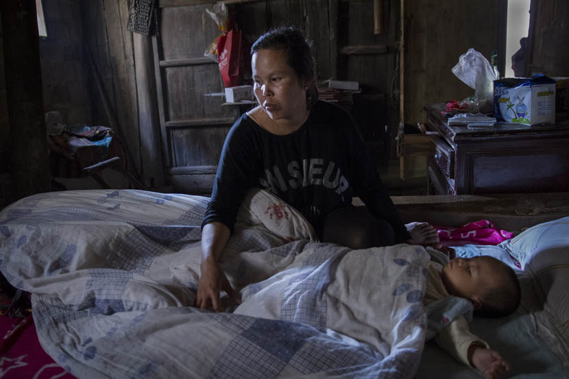 Buntha sits next to her sleeping baby in the morning in Huanggang Town, Jiangxi province, June 2015. She has to take care of the baby and do housework mainly on her own, because her husband works long hours. Courtesy of Cong Yan
