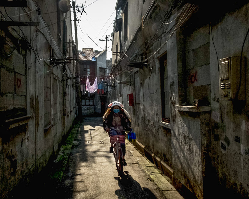 A young woman rides along an alley in Laoximen, Shanghai, Jan. 17, 2019. Daniel Holmes/Sixth Tone