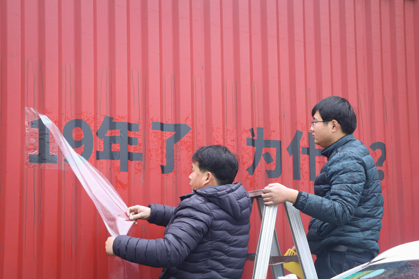 Employees of a print shop apply “For 19 years, why?” onto a truck in Shanghai, Jan. 11, 2019. Yin Yijun/Sixth Tone