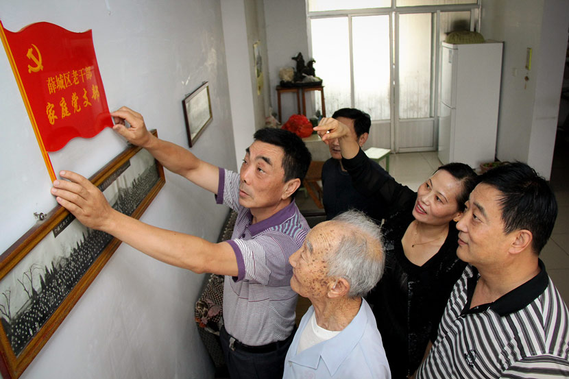 A Party member hangs a “Party Family Branch” sign in a community activity room in Zaozhuang, Shandong province, June 29, 2012. VCG