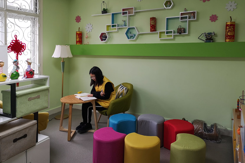 A volunteer reads a book in an activity room designed for counseling sessions for families of hospice patients at Chengjiaqiao Community Health Service Center, Shanghai, March 5, 2019. Ni Dandan/Sixth Tone