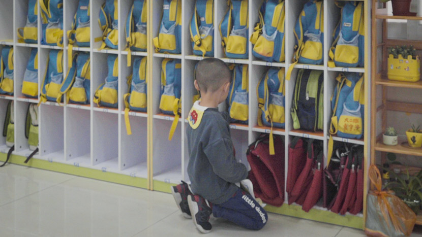 A child looks at shelves of backpacks in Dongguan, Guangdong province, March 25, 2019. Liu Jingwen/Sixth Tone