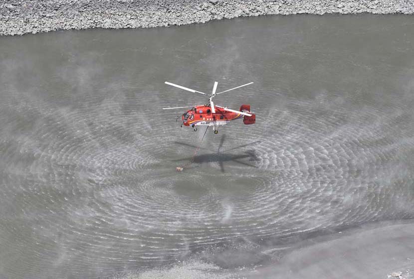 A rescue helicopter fetches water to put out a deadly forest fire that killed 27 firefighters and three people from the local fire department in Muli County, Liangshan Yi Autonomous Prefecture, Sichuan province, April 2, 2019. Liu Kun/Xinhua