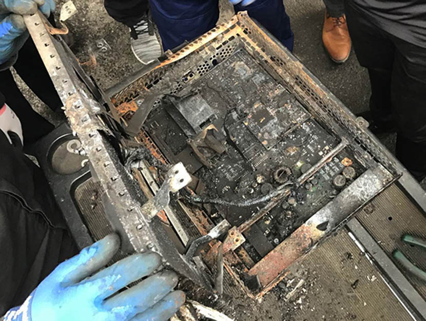 Inspectors examine the burned battery of the Tesla Model S days after it caught fire. From The Paper