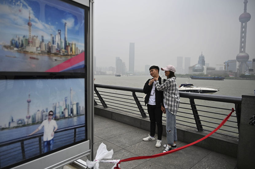 A couple pose for a photographer on the waterfront of the Bund along the Huangpu River during a May Day holiday in Shanghai, May 1, 2019. Hector Retamal/AFP/VCG