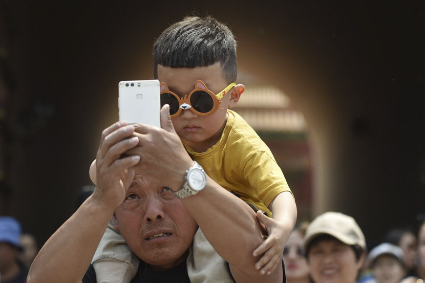 A man takes a selfie with a young boy near the Forbidden City palace complex in Beijing, May 3, 2019. Greg Baker/AFP/VCG