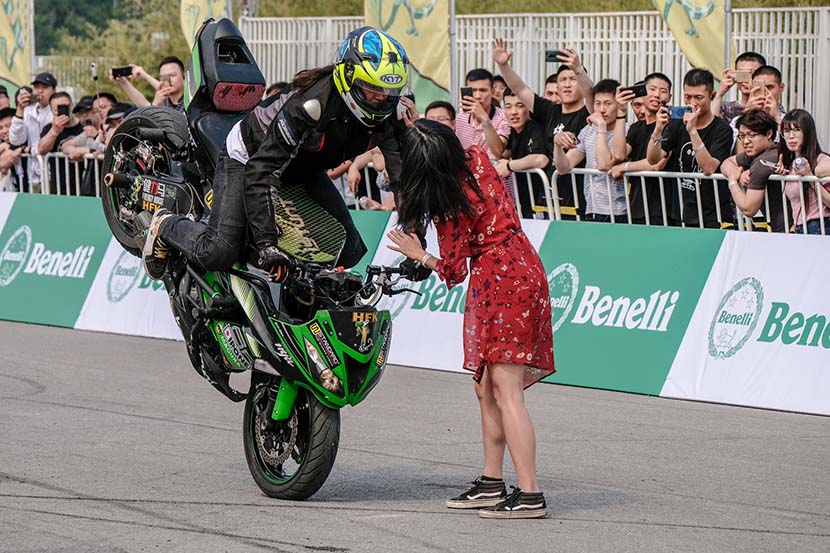 A woman interacts with a motorcyclist during the 19th China (International) Motor Expo and Forum 2019, also known as Motor China 2019, in Beijing, May 11, 2019. IC