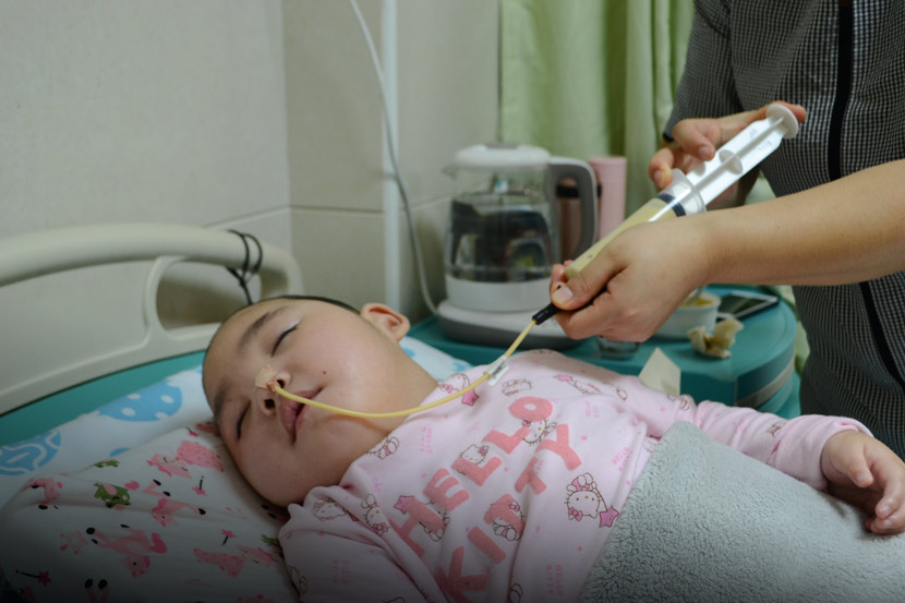 Liu Xuejie feeds Niuniu with a syringe at a hospital in Guangzhou, Guangdong province, April 14, 2019. Fan Liya/Sixth Tone