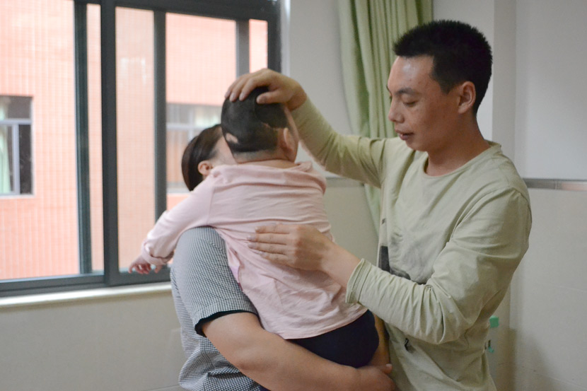 Zhang Shaofeng helps Niuniu loosen mucus by patting her on the back at a hospital in Guangzhou, Guangdong province, April 14, 2019. Fan Liya/Sixth Tone