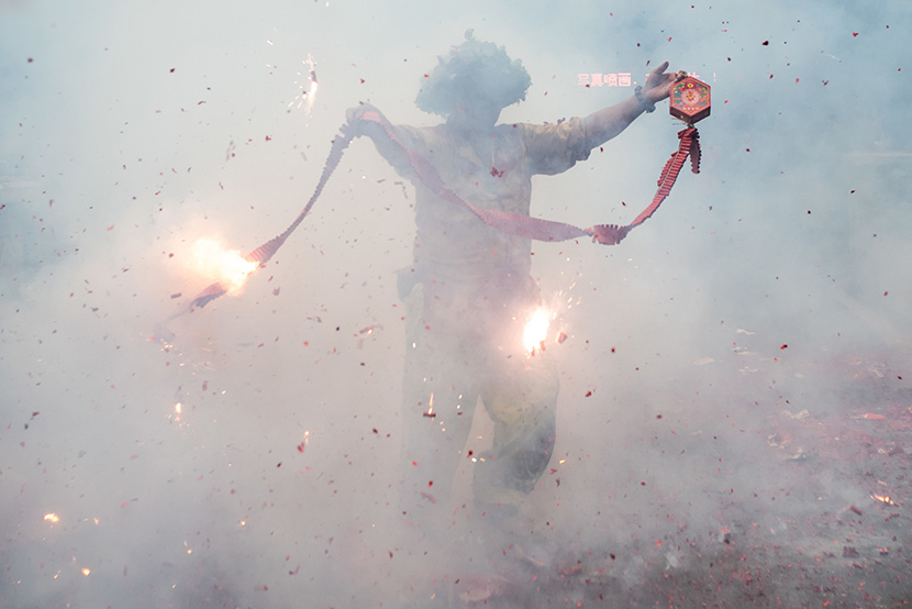A man holds a lit firecracker while celebrating the Dragon Boat Festival holiday in Guangzhou, Guangdong province, June 6, 2019. IC