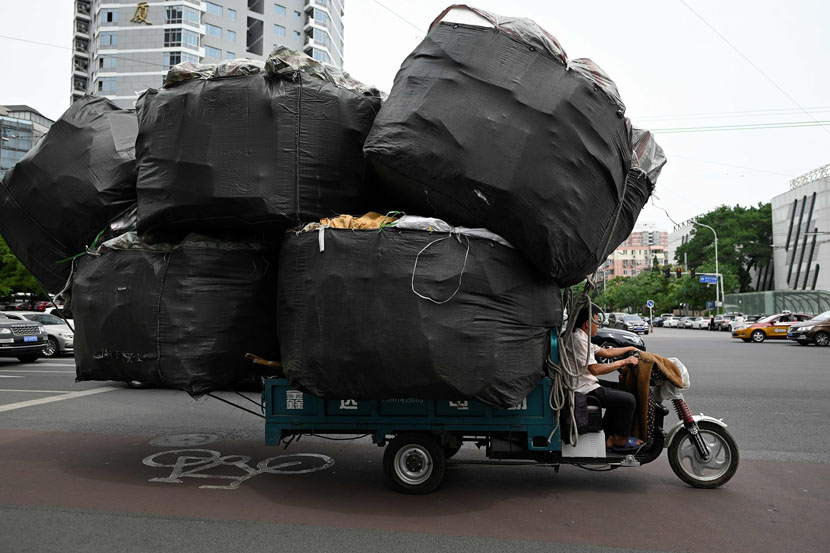 A man drives an electric tricycle loaded with lightweight recyclables in Beijing, June 5, 2019. Wang Zhao/AFP/VCG