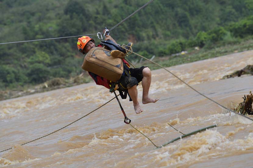 A rescuer crosses the river to evacuate people trapped after heavy rain triggered a flood in Heyuan, Guangdong province, June 11, 2019. Seven people were killed and one went missing after the storm. Cai Zirong/VCG