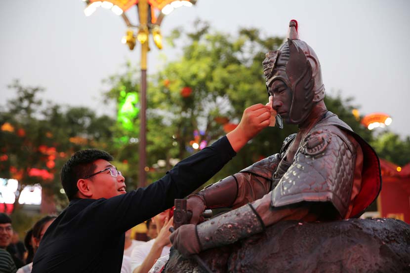 A tourist wipes sweat off an actor dressed as a terra cotta warrior in Xi’an, Shaanxi province, June 13, 2019. Wei Yongxian/VCG