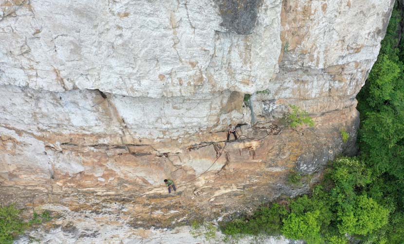 Two road workers clear rocks while building cliffside roads in Badong County, Hubei province, June 10, 2019. Yang Peishun/Xinhua