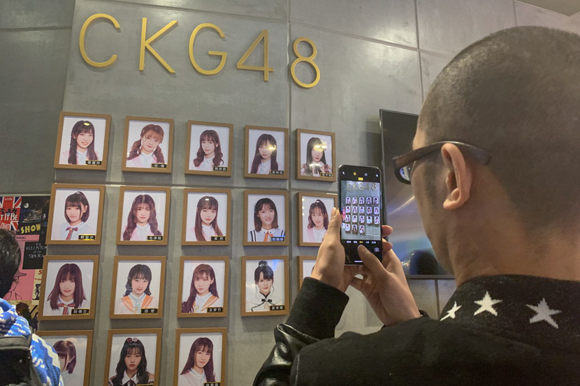 A fan takes a picture of the portraits of CKG48 members in Chongqing, March 16, 2019. Yin Yijun/Sixth Tone