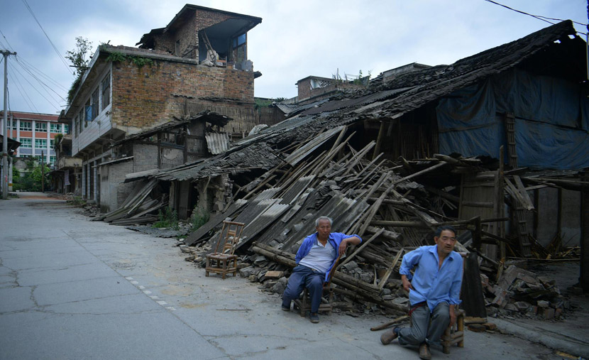 Two men sit in front of a collapsed building after an earthquake in Shuanghe Town, Sichuan province, June 18, 2019. Liu Zhongjun/CNS/VCG
