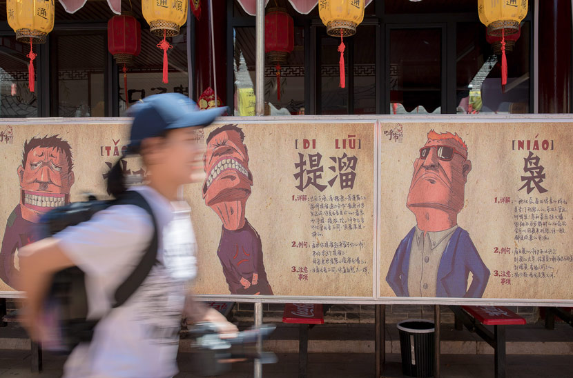 A woman walks past posters of an exhibition about the city’s local dialect in Hohhot, Inner Mongolia Autonomous Region, May 23, 2019. Ding Genhou/VCG