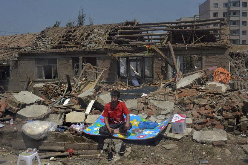 A man sits in front of a house that was destroyed by a tornado in Kaiyuan, Liaoning province, July 4, 2019. VCG