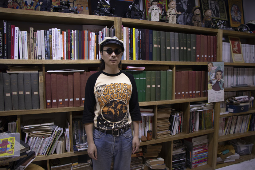 Feng Guangjun poses for a photo in front of his collection of old books and magazines at vintage shop Beachhunter in Hangzhou, Zhejiang province, June 18, 2019. Kenrick Davis/Sixth Tone