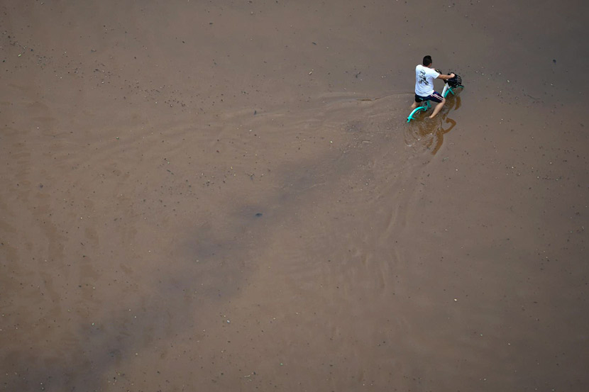 A cyclist rides through water covering the streets in Kunming, Yunnan province, July 20, 2019. A heavy rainstorm had hit the southwestern Chinese city, causing flooding in low-lying areas. Liu Ranyang/CNS/VCG
