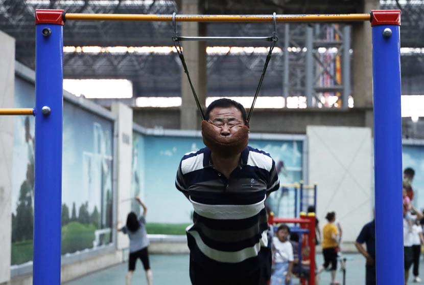 A man performs an exercise that is capable of alleviating the symptoms of cervical spondylosis in Shenyang, Liaoning province, July 11, 2019. IC
