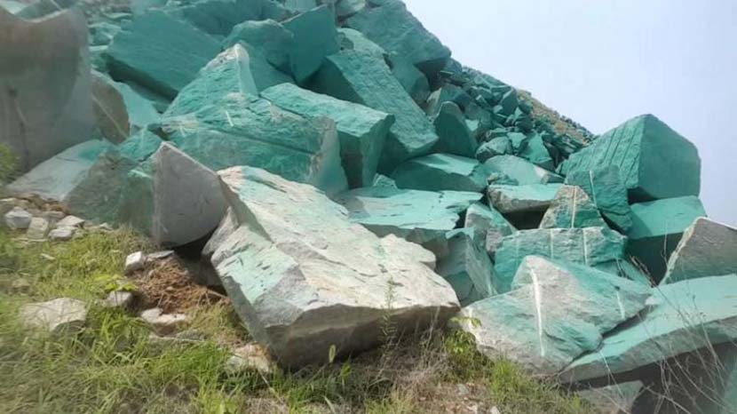 Rocks outside a stone processing plant are shown painted green in Xintai, Shandong province, 2019. @齐鲁网 on Weibo