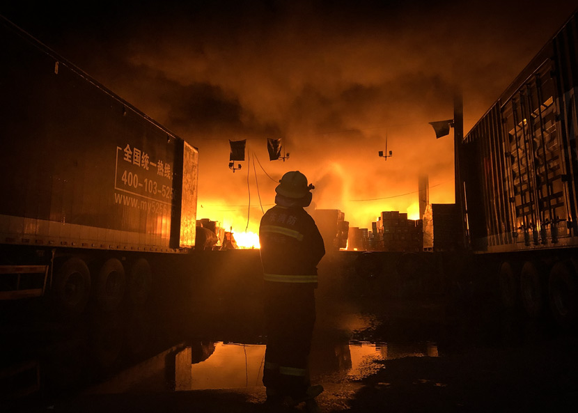 A firefighter watches on as a fire burns in a logistics center in Guangzhou, Guangdong province, July 30, 2019. VCG
