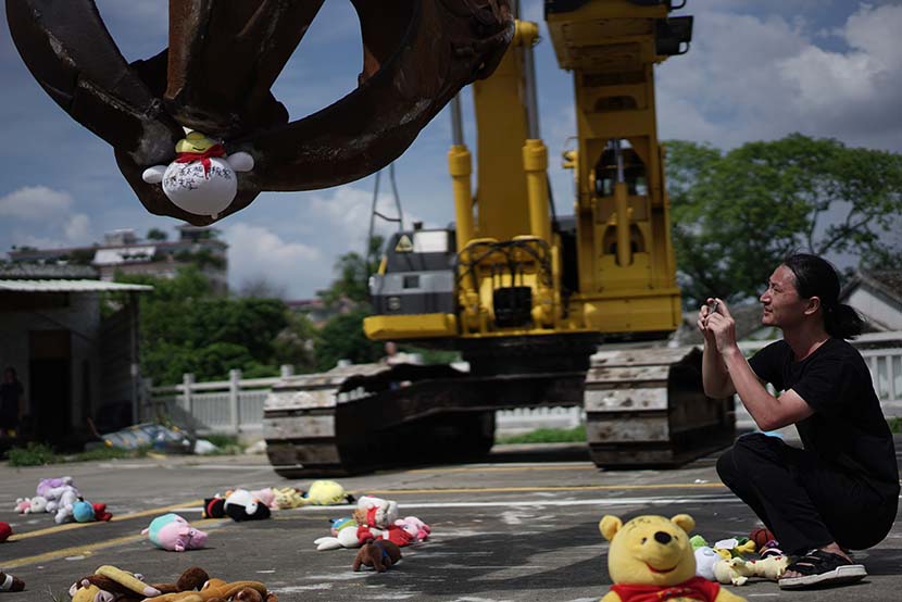 Chinese artist Nut Brother photographs an excavator picking up a doll during the performance of his art installation in Shenzhen, Guangdong province, Aug. 4, 2019. Qiu Rong for Sixth Tone