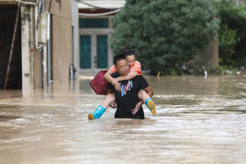 A man carries a woman through floodwaters caused by Typhoon Lekima in Dajing Town in Yueqing, Zhejiang province, Aug. 10, 2019. Lekima made landfall in Zhejiang early Saturday morning. Zhejiang Daily/IC