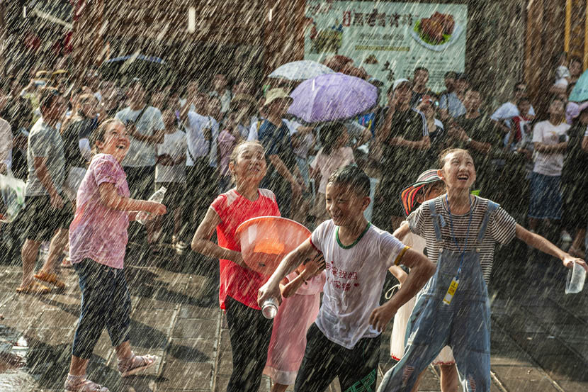 Children play under falling water during a water-sprinkling festival celebrated in Enshi, Hubei province, Aug. 9, 2019. Zhou Ahan/VCG