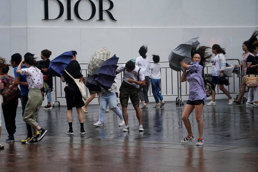 Pedestrians are buffeted by strong winds as Typhoon Lekima approaches Shanghai, Aug. 10, 2019. Aly Song/Reuters/VCG