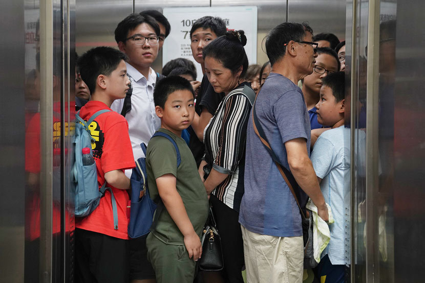 Students and their family members crowd an elevator in what’s been called the “tutor tower” to attend extracurricular classes in Beijing, July 15, 2019. Cai Yingli/Caixin/VCG