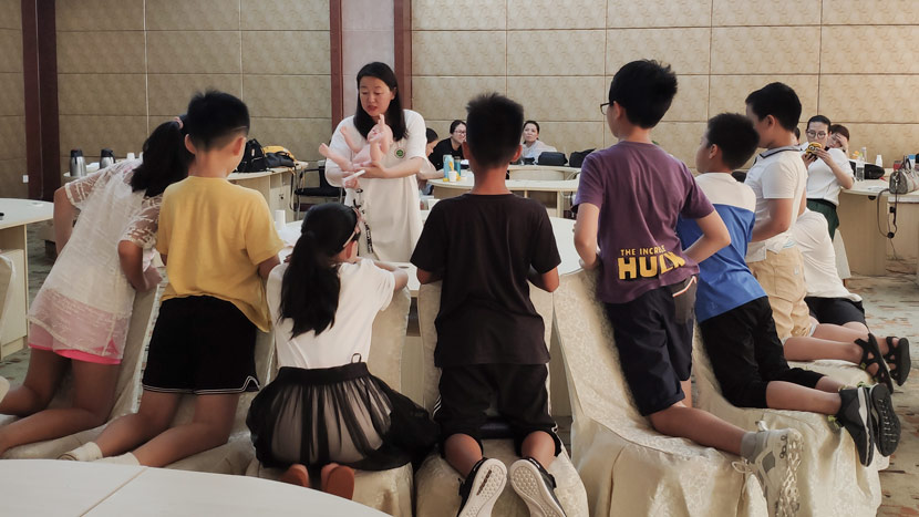 Sex education lecturer Wang Yi shows children how to use a tampon on a doll during a sex education summer camp in Qingdao, Shandong province, Aug. 4, 2019. Fan Yiying/Sixth Tone