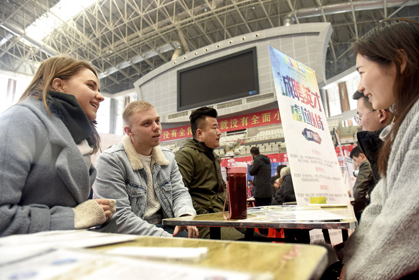 Staff at a training center talk to people at a job fair in Huainan, Anhui province, Feb. 23, 2019. Chen Bin/VCG