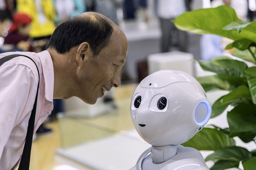An attendee looks at a semi-humanoid robot at the World Artificial Intelligence Conference (WAIC) in Shanghai, Aug. 29, 2019. Qilai Shen/Bloomberg/VCG