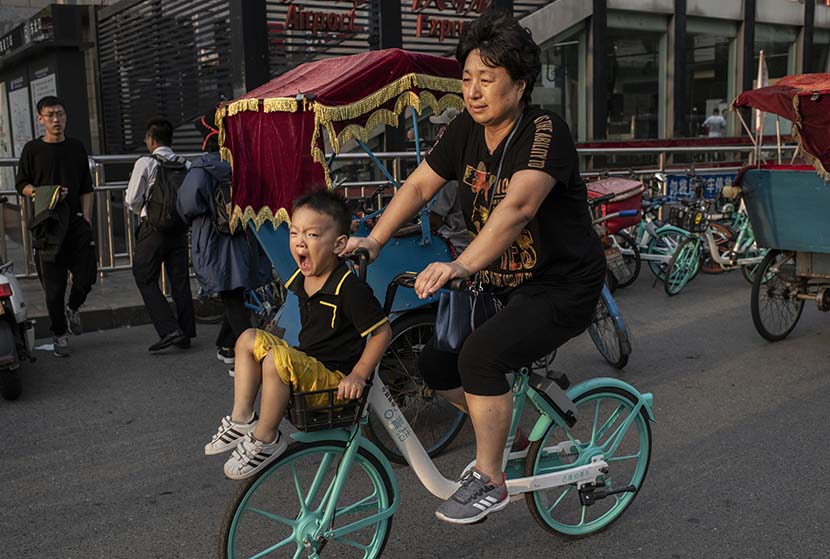A young boy yawns as he’s pedaled through rush hour in Beijing, Sept. 20, 2019. Kevin Frayer/Getty Images/VCG