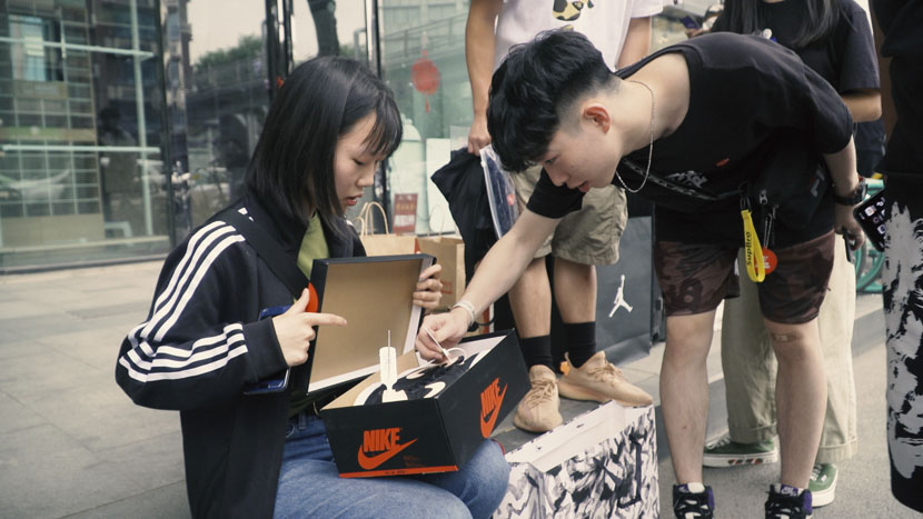 A man checks the label of a pair of sneakers in Chengdu, Sichuan province, May 2019. Sun Zhichao for Sixth Tone