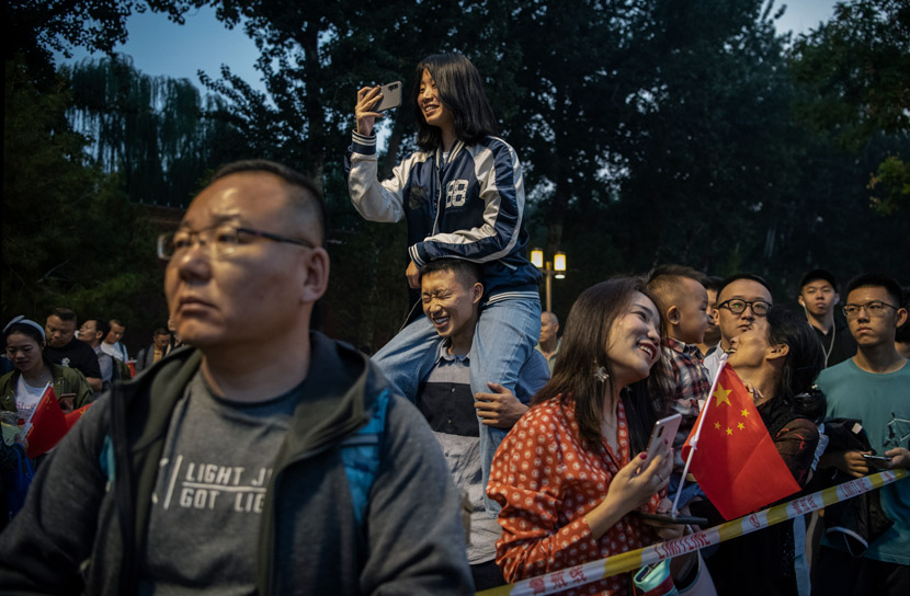 Tourists strain to catch a glimpse of the daily flag raising ceremony in Beijing’s Tiananmen Square, Sept. 30, 2019. Kevin Frayer/VCG