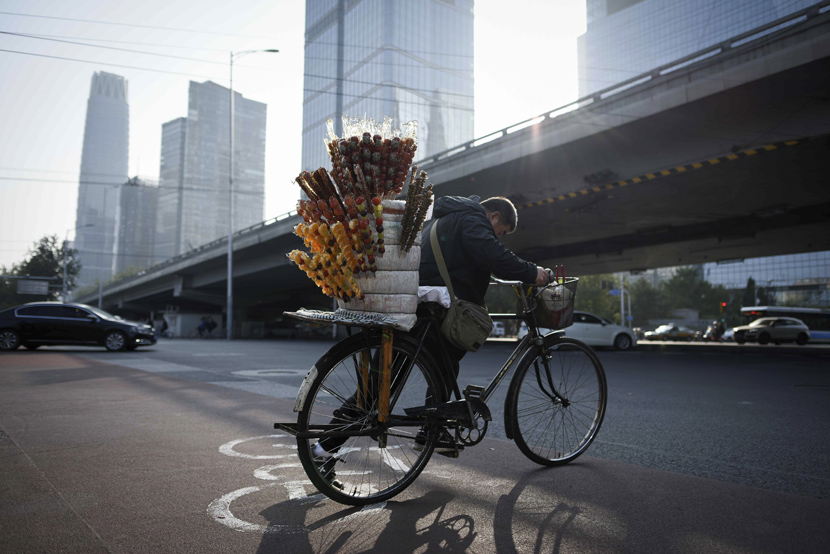 A vendor rides his bicycle across a street in Beijing’s central business district, Oct. 18, 2019. Wang Zhao/AFP/VCG