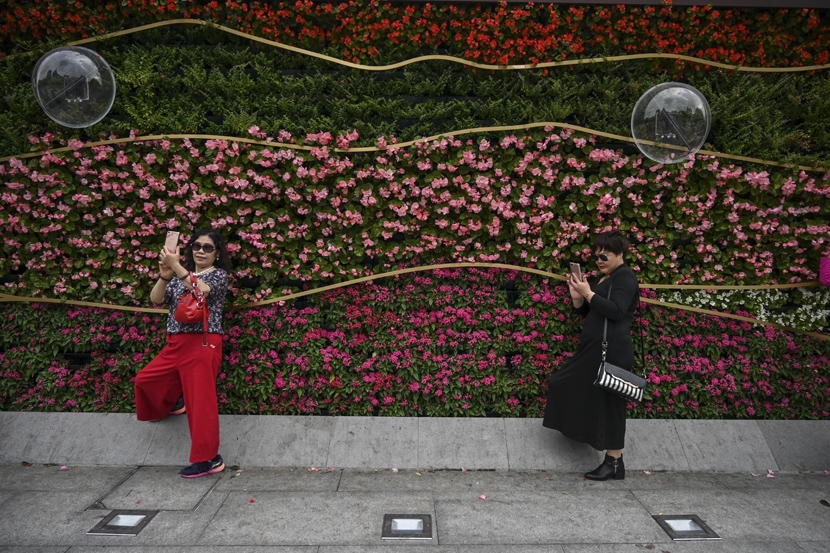 Women take selfies next to the promenade along the Bund in Shanghai, Oct. 14, 2019. Hector Retamal/AFP/VCG