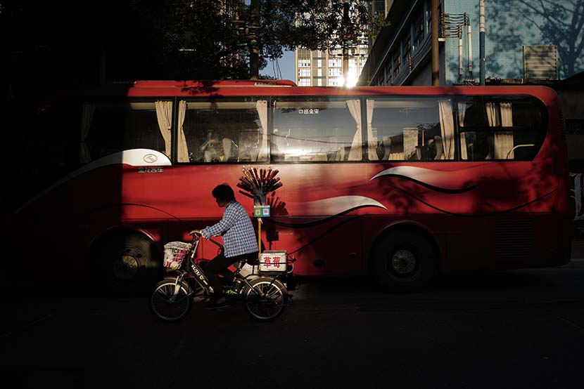 An ice-sugar gourd vendor passes a bus in Guangzhou, Guangdong province, Nov. 21, 2019. VCG