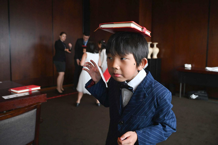 A boy practices balancing a book on his head during an etiquette and manners class in central Shanghai, June 1, 2019. Etiquette classes can cost almost $100 an hour. Hector Retamal/AFP/VCG