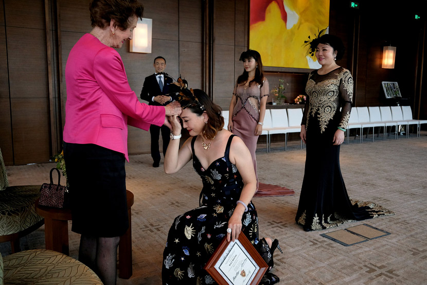 A participant takes a knee before former Australian model June Dally-Watkins after receiving an etiquette certificate in Guangzhou, Guangdong province, Oct. 8, 2017. Bobby Yip/Reuters/VCG