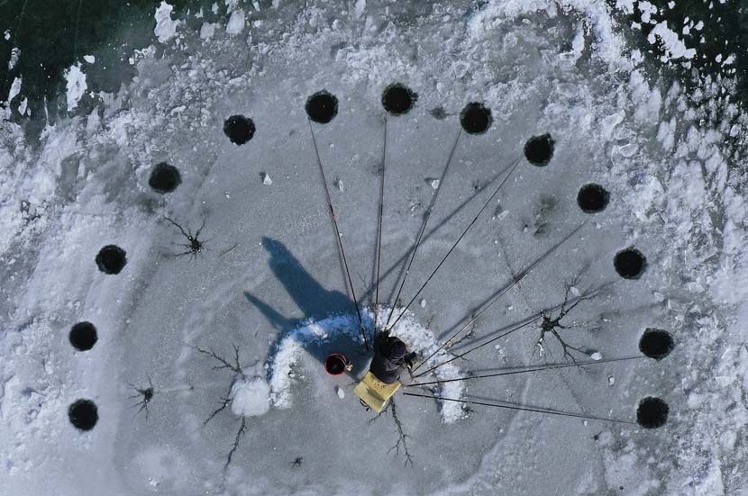 A fisherman monitors multiple rods while ice fishing in Beijing, Dec. 7, 2019 in Beijing, China. Ma Wenxiao/VCG