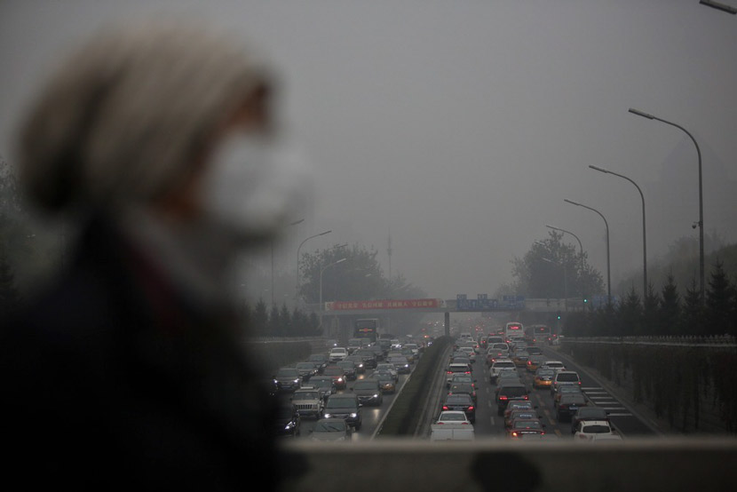A woman wearing a mask walks along an overpass in Beijing, Nov. 18, 2016. Xie Kuangshi for Sixth Tone