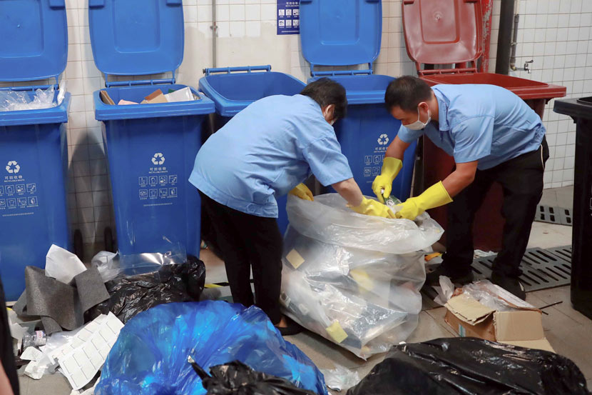 Workers sort waste in front of trash bins in Shanghai, July 1, 2019. Tuchong