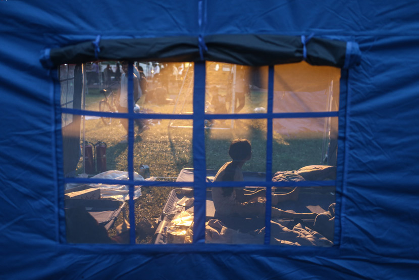 A child looks into the distance from inside a tent at a temporary camp set up for earthquake survivors in Changning County, Sichuan province, June 18, 2019. Peng Ziyang/Beijing News/IC