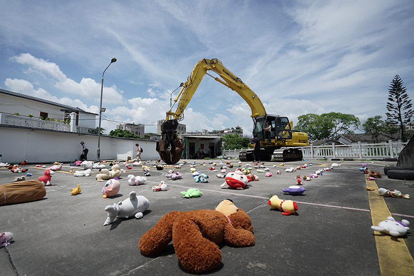 An excavator picks up dolls during an art installation by Chinese artist Nut Brother in Shenzhen, Guangdong province, Aug. 4, 2019. Qiu Rong for Sixth Tone