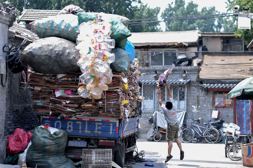 A recycler throws cardboard onto his truck in Beijing, June 10, 2018. Tuchong