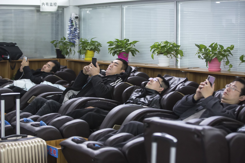 Passengers use shared massage chairs at a railway station during the first day of the Spring Festival travel rush in Hangzhou, Zhejiang province, Jan. 10, 2020. Chen Zhongqiu for Sixth Tone